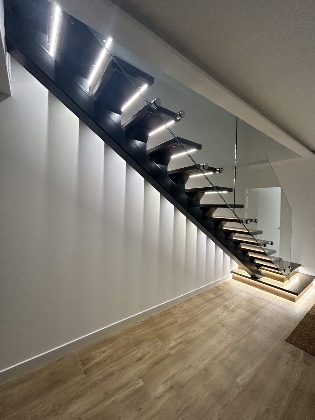 Escalera metálica con peldaños de madera y barandilla de vidrio